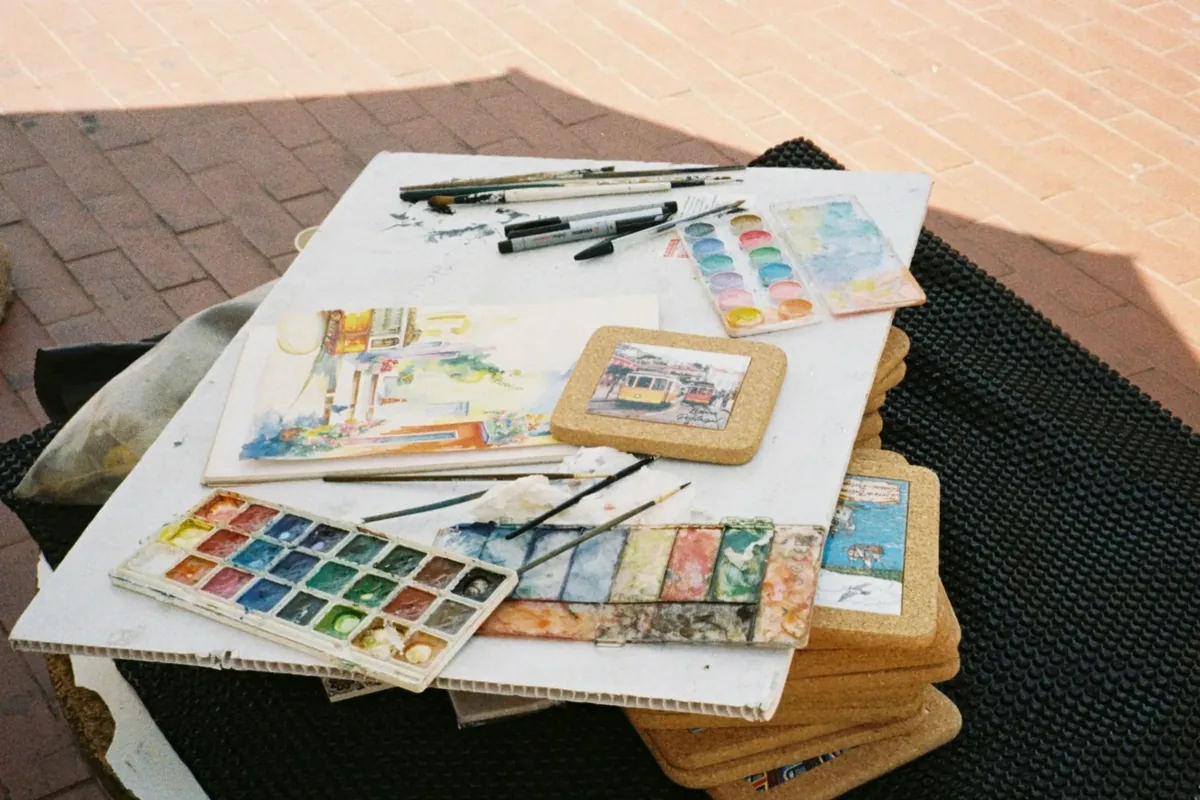 Watercolours, brushes, pens and paper laid out on a table