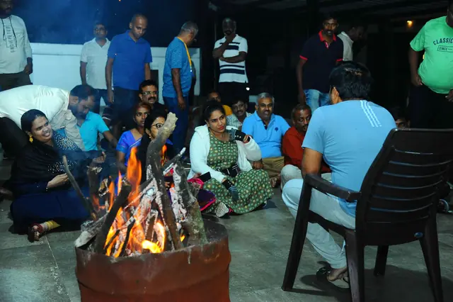 இரவில் நெருப்பைச் சுற்றி அமர்ந்திருக்கும் பங்கேற்பாளர்கள்