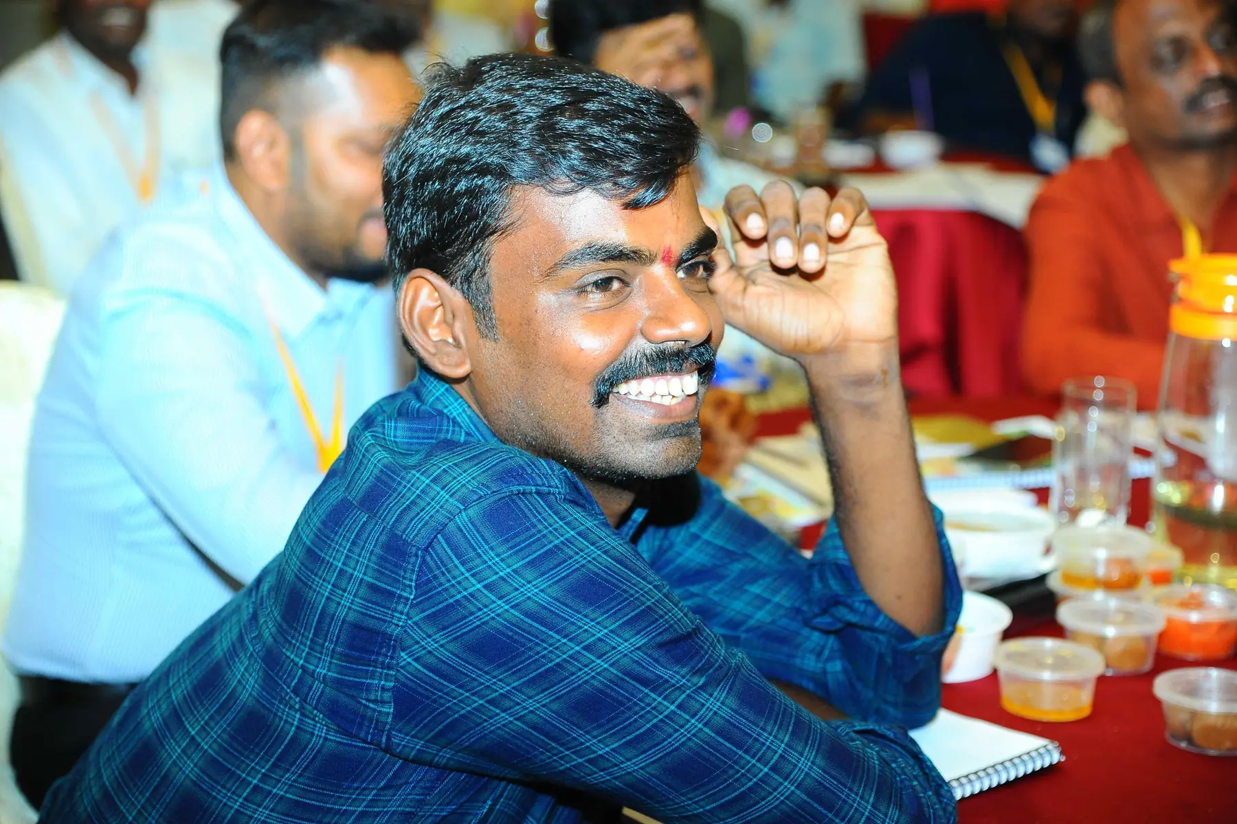 மேசையில் அமர்ந்து சிரிக்கும் ஒரு பங்கேற்பாளர்