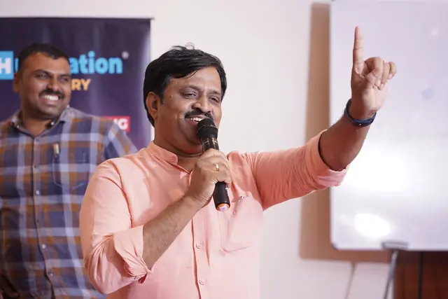 மைக்கைப் பிடித்தபடி மேலே சுட்டிக்காட்டும் சுரேகா சுந்தர்